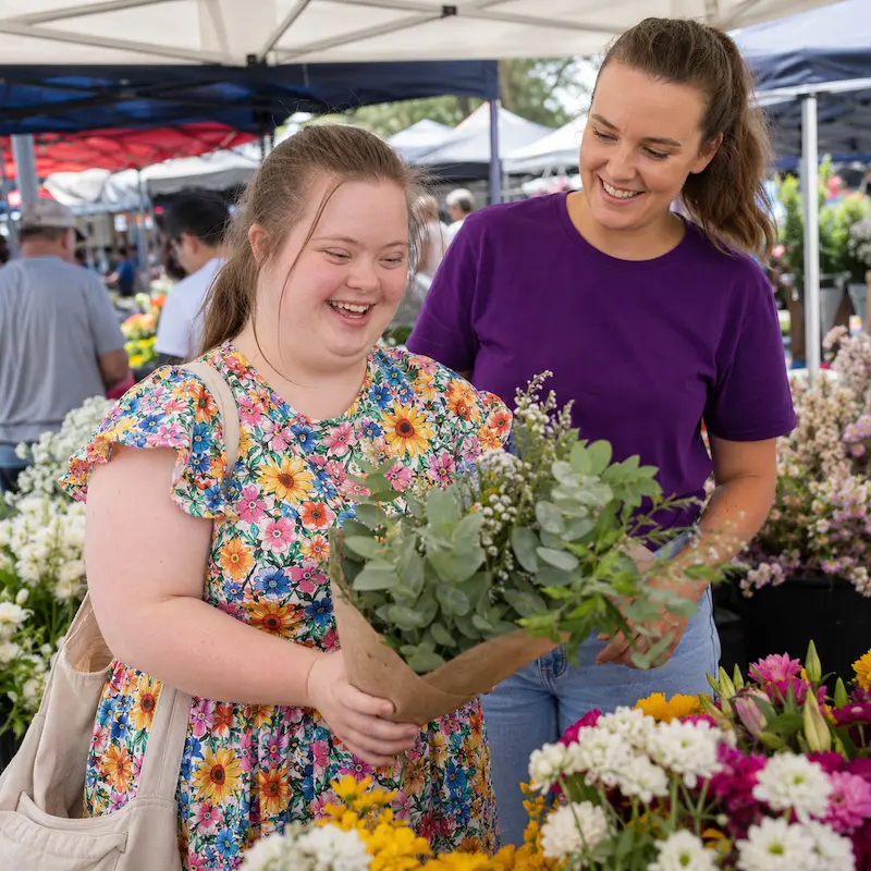 Participant buying flowers while support worker is assiting her